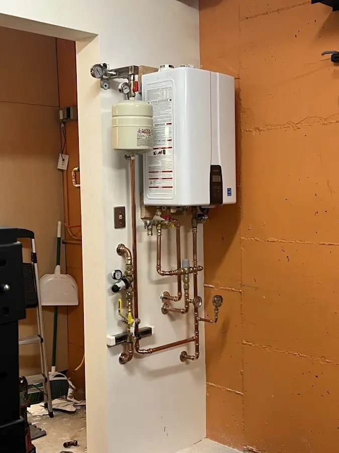 Plumbing technician inspecting water heater connections in Pueblo West
